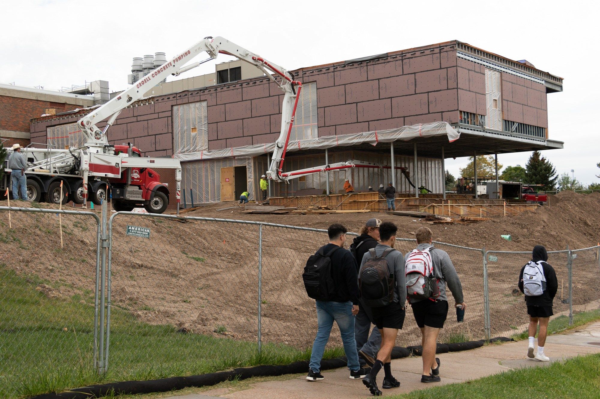 Students walk by as crews pour concrete walls for the north addition to Chadron State College's Math Science COIL Sept. 29, 2021.