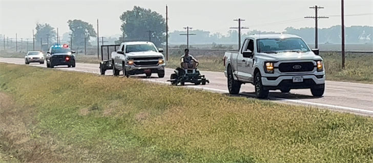 Hunter Arterburn rides the mower between two pickups on his way from Chappell to Sidney.