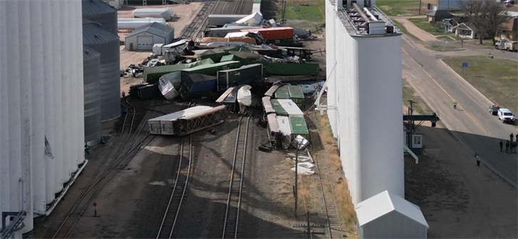 The aerial view shows derailed train cars nearly sandwiched between the structures at the west end of the Frenchman Valley Coop .