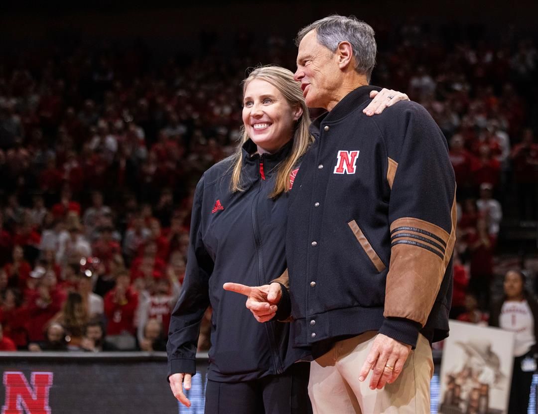 Newly named Nebraska volleyball head coach Dani Busboom Kelly, left, stands midcourt with retiring volleyball coach John Cook, right, during a timeout acknowledgment as Illinois plays against Nebraska in the first half of an NCAA college basketball game T
