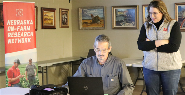 Jessica Groskopf, UNL Ag Economist. gave a presentation at the On-Farm Research event on Carbon Credits. She watches as John Thomas, Nebraska Extension Educator, sitting, loads her presentation.