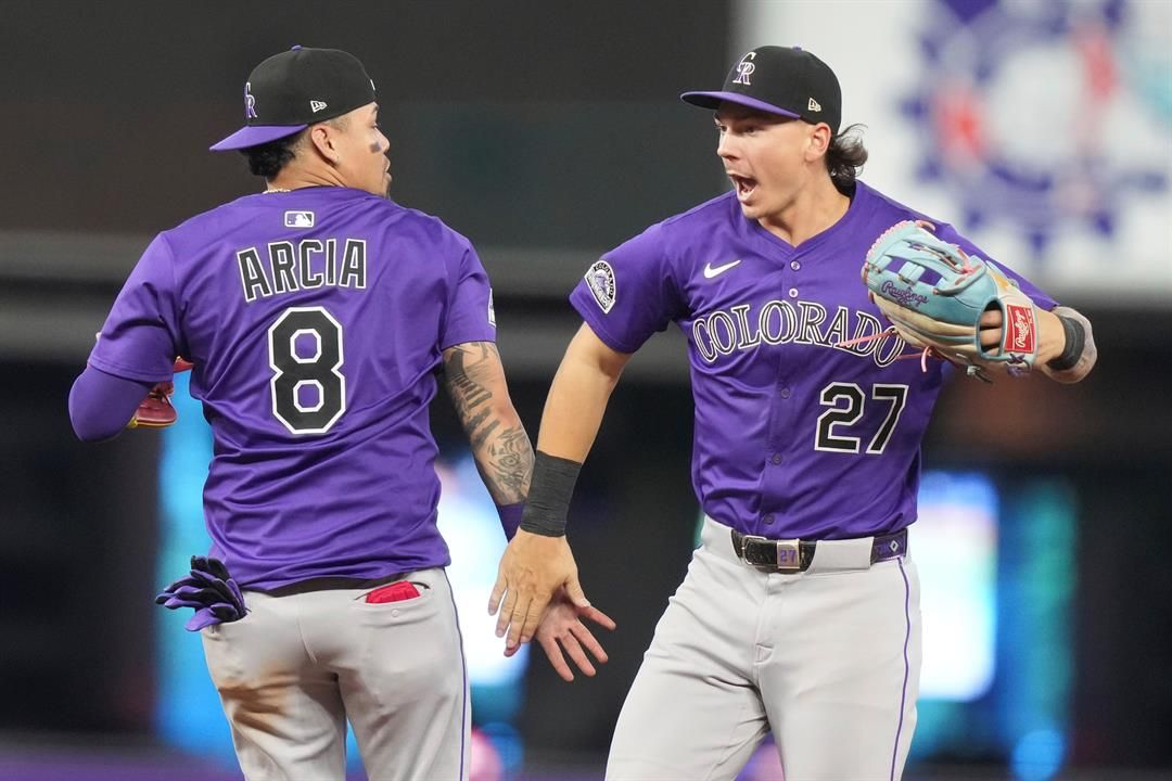 Colorado Rockies shortstop Orlando Arcia (8) and left fielder Jordan Beck (27) high-five after the Rockies defeated the Miami Marlins in a baseball game, Wednesday, June 4, 2025, in Miami.