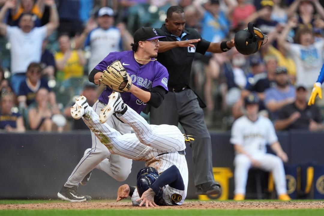 Milwaukee Brewers' Joey Ortiz, bottom, rolls after scoring on a wild pitch during the 10th inning of a baseball game against the Colorado Rockies, Sunday, June 29, 2025, in Milwaukee.