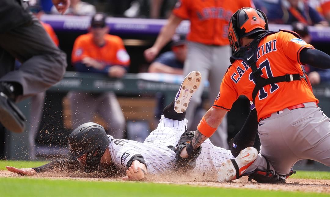Houston Astros catcher Victor Caratini, right, tags out Colorado Rockies' Tyler Freeman as he tries to score on triple hit by pinch-hitter Miceky Moniak in the seventh inning of a baseball game, Thursday, July 3, 2025, in Denver.