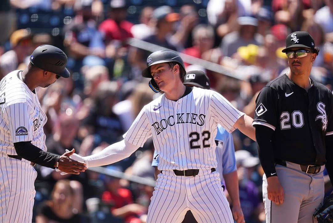 Colorado Rockies third base coach Andy González, left, congratulates Mickey Moniak after his triple to drive in two runs as Chicago White Sox third baseman Miguel Vargas, right, looks on in the fifth inning of a baseball game Sunday, July 6, 2025.