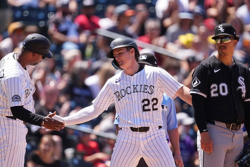 Colorado Rockies third base coach Andy González, left, congratulates Mickey Moniak after his triple to drive in two runs as Chicago White Sox third baseman Miguel Vargas, right, looks on in the fifth inning of a baseball game Sunday, July 6, 2025.