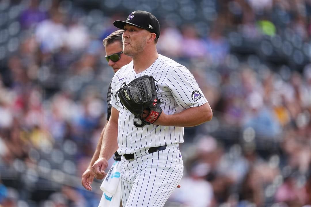 Colorado Rockies relief pitcher Seth Halvorsen, front, is escorted from the mound by head trainer Keith Dugger after throwing only five pitches to Pittsburgh Pirates pinch hitter Spencer Horwitz in the ninth inning of a baseball game Saturday, Aug. 2, 202