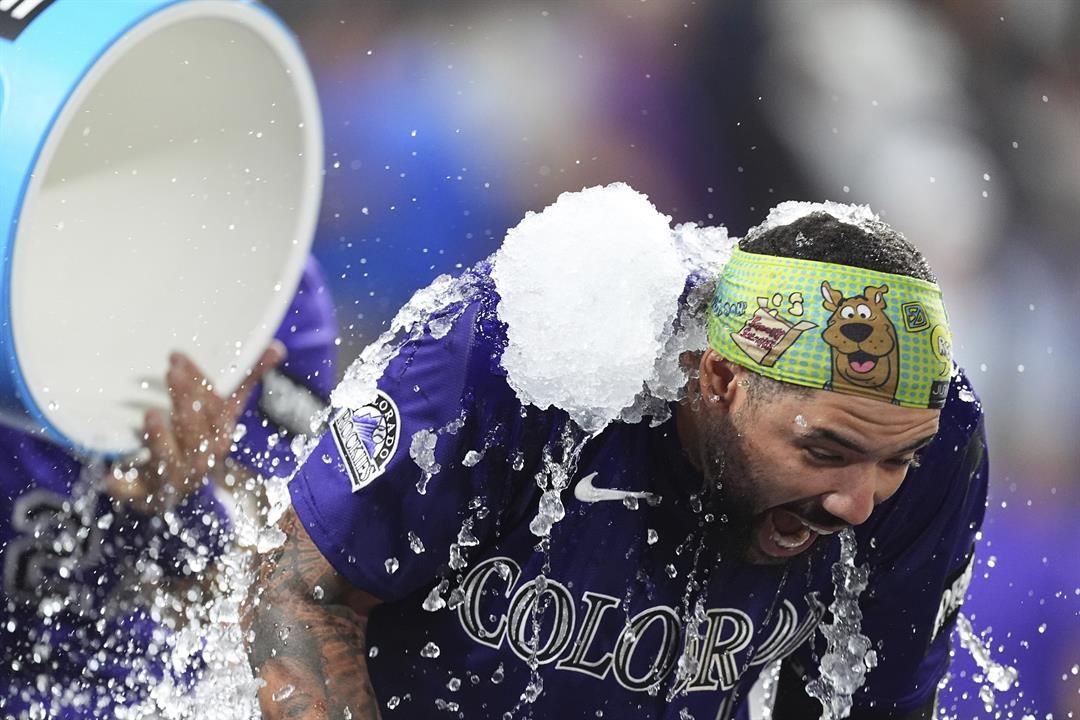 Colorado Rockies' Warming Bernabel, right, is doused by teammate Jordan Beck, back left, after hitting a walk-off RBI single off Los Angeles Dodgers relief pitcher Justin Wrobleski in the ninth inning of a baseball game Monday, Aug. 18, 2025, in Denver.