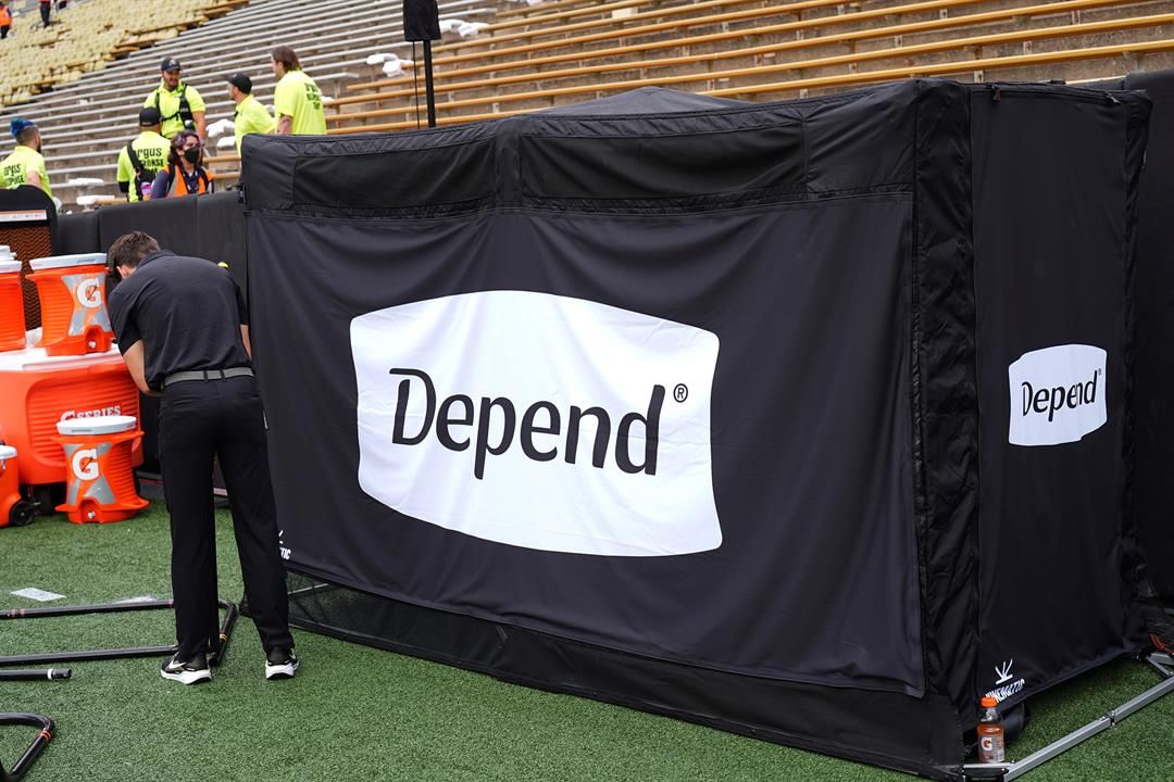 A field worker sets up equipment next to a tent containing a bathroom in the team box on the Colorado sideline before an NCAA college football game against Georgia Tech Friday, Aug. 29, 2025, in Boulder, Colo.