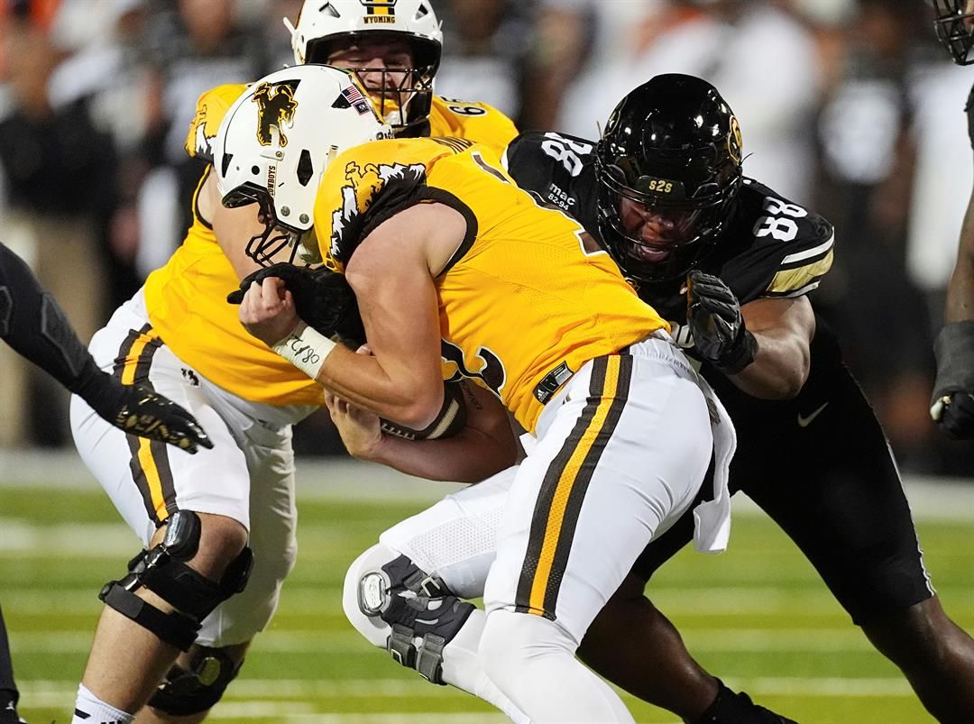 Wyoming quarterback Kaden Anderson, front, is stopped after a short gain by Colorado defensive tackle Amari McNeill (88) in the first half of an NCAA college football game Saturday, Sept. 20, 2025, in Boulder, Colo.