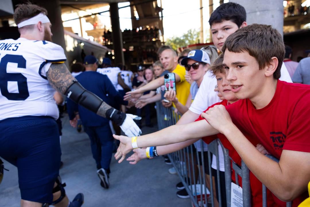 Nebraska fan Kellen Otto, 15, right, of Firth, Neb., high fives Michigan players as they exit the field following Michigan's 30-27 win over Nebraska in an NCAA college football game, Saturday, Sept. 20, 2025, in Lincoln, Neb.