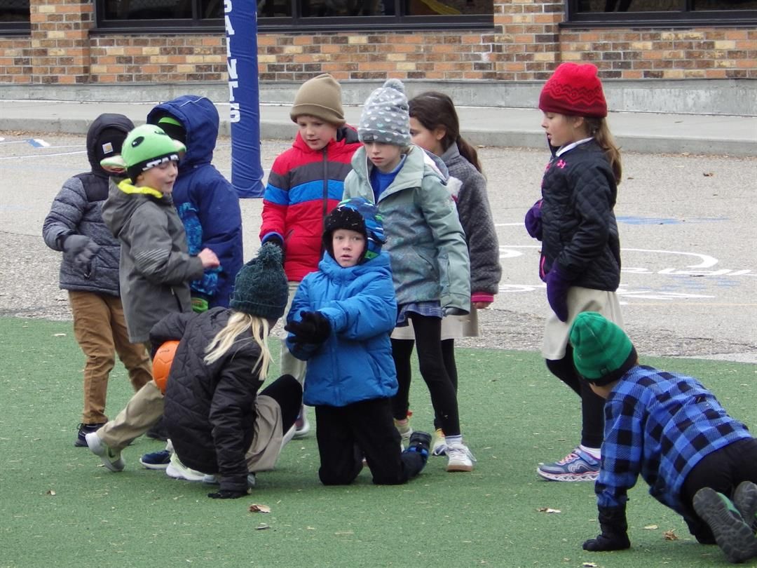 Children wearing coats, hats and gloves play with a ball Friday, Nov. 7, 2025, at St. Mary's Elementary School in Bismarck, N.D.