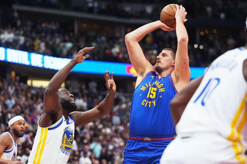 Denver Nuggets center Nikola Jokic (15) looks to shoot for a basket over Golden State Warriors forward Draymond Green (23) in the first half of an NBA Cup basketball game Friday, Nov. 7, 2025, in Denver.